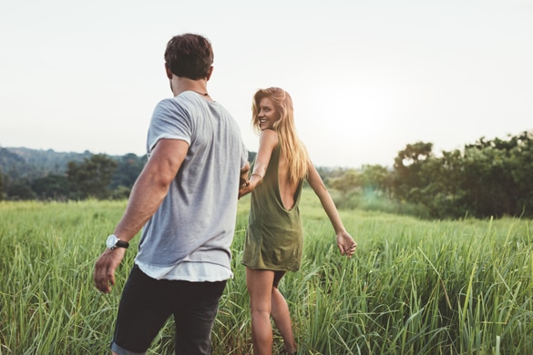 rear-view-shot-of-virgo-woman-walking-with-her-virgo-man-on-grass-field